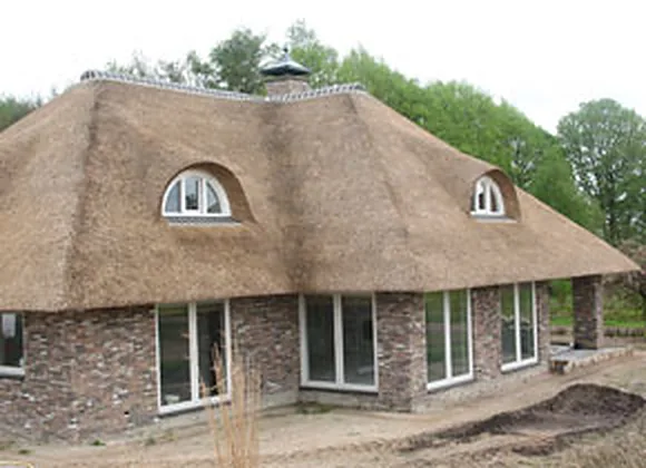 Bungalow met een nieuw rieten dak, ronde dakkapellen en een schoorsteen