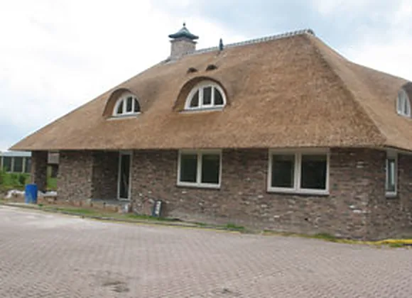 Nieuw rieten dak op een vrijstaande woning met ronde dakkapellen