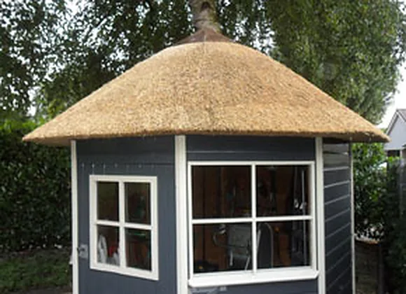 Tuinhuis met witte kozijnen en een rieten dak