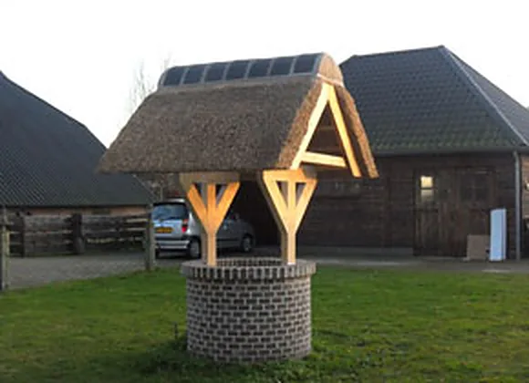 Waterput met een rieten kapje voor een schuur